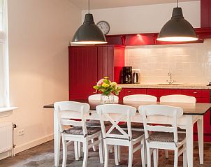 Moderne keuken in Vakantiehuis in Haastrecht met rode kasten en ruime eettafel.