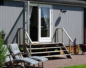 Terras van Huisje in Haastrecht, vakantieaccommodatie in Haastrecht, Zuid-Holland, met relaxstoelen en groene omgeving.