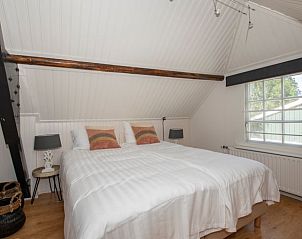 Zolderkamer in Vakantiehuis in Aarlanderveen met houten balken en knus bed.