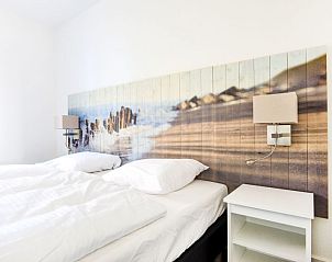 Slaapkamer Vakantiehuis Tapuit 6, Noordwijk, met comfortabel bed en strandthema, perfecte rustplek.