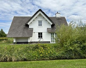 Achterzijde Vakantiehuis Tapuit 6, Noordwijk, met rieten dak en groene omgeving aan de Noordzeekust.