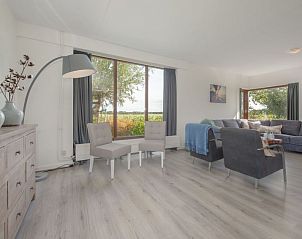 Stijlvolle woonkamer in Vakantiehuis Groepsaccommodatie 12, Hellevoetsluis, met grote ramen voor veel natuurlijk licht.