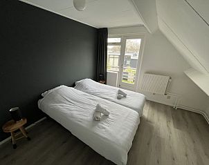 Slaapkamer met balkon in Vakantiehuis Groepsaccommodatie 12, Hellevoetsluis, voor een rustige nachtrust in Zuid-Holland.