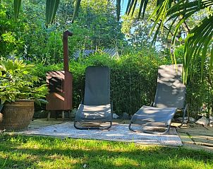 Ontspannende ligstoelen in de tuin van vakantiehuisje in Groesbeek, Rijk van Nijmegen, omgeven door weelderige natuur.