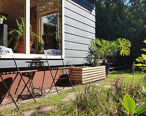 Zonnige zithoek buiten vakantiehuisje in Groesbeek, omringd door groen in het Rijk van Nijmegen, Gelderland.