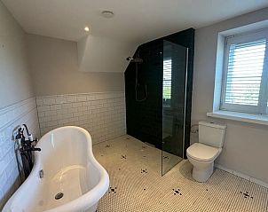 Moderne badkamer met bad en douche in Huisje in Overasselt, een charmant vakantieverblijf in Gelderland.